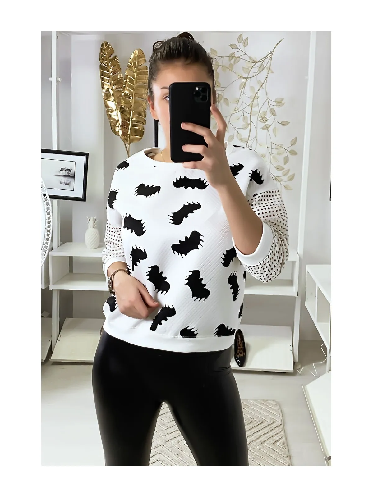 Pull blanc à motif chauve-souris et manches à trou quadrillé.