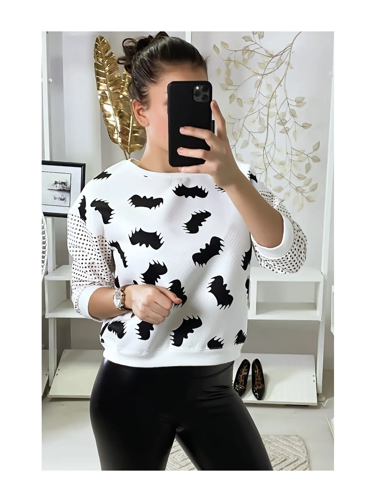 Pull blanc à motif chauve-souris et manches à trou quadrillé.